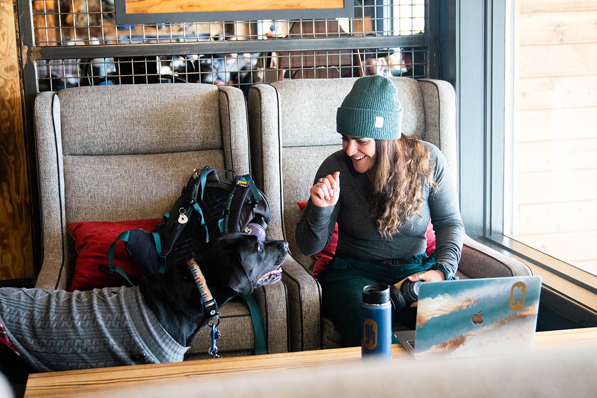 Andrea Rosenthal works on her laptop at StarterHaus Breck as her dog looks on.