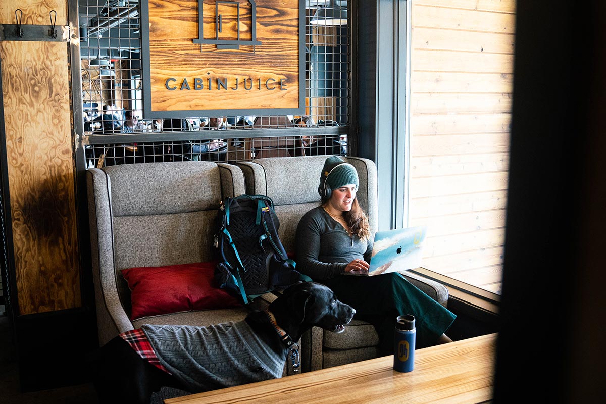 Andrea Rosenthal works on her laptop at StarterHaus Breck as her dog looks on.